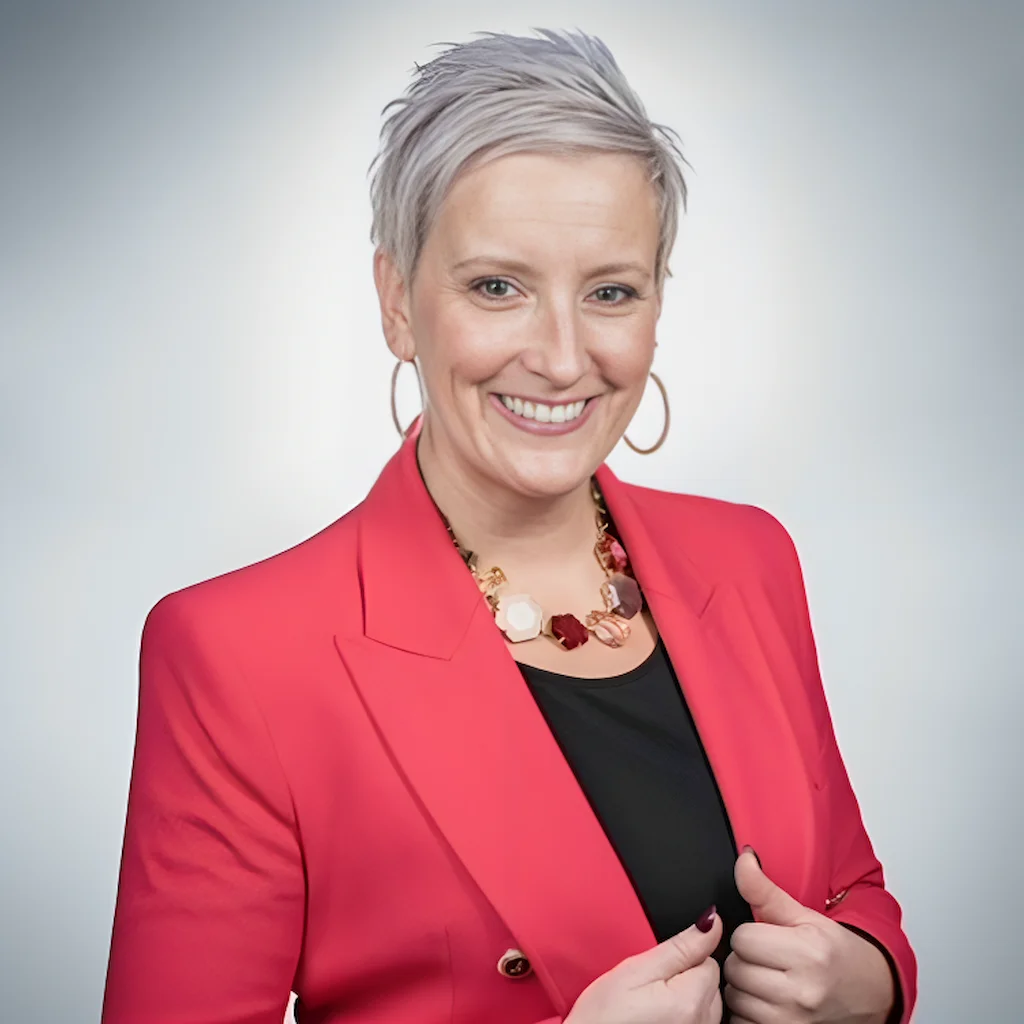 Our CEO Lori-Ann Duguay in a red blazer, smiling confidently, promoting DiSC-Based Leadership & Management Skills Development 2025.